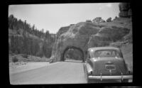 H. H. West's car parked in front of a rock tunnel in Red Canyon, 1942