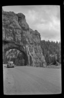H. H. West's car driving through a rock tunnel in Red Canyon, 1942