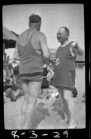 E. M. Buckius converses with another man on the beach, Hermosa Beach, about 1932