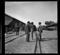 John A. Muir, E. L. Swaine and Clarence Stephens stand on the tracks at the Whittier depot, Whittier, 1899