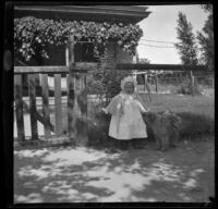 Lucille McIntyre stands with a dog in front of the McIntyre family home, Indio, 1900