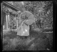 Lucille McIntyre holds a parasol in stands in the front yard of the McIntyre family home, Indio, 1900