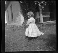Lucille McIntyre stands in the front yard of the McIntyre family home with her back to the camera, Indio, 1900