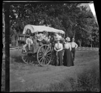 Group sits on a horse-drawn covered wagon, Elliott vicinity, 1900