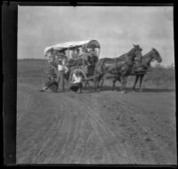 Group sits on covered, horse-drawn cart while Independence (Inda) Stevens and two other man stand next to it, Elliott vicinity, 1900