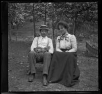 H. H. West and Emma Manker sit together on a low bench, Elliott vicinity, 1900