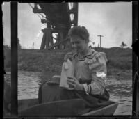 Margaret Burris eats a cookie while sitting on a boat, Elliott vicinity, 1900