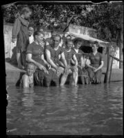 H. H. West sits on the edge of an outdoor swimming pool known as Lewis Lake with his cousins and friends, Elliott vicinity, 1900