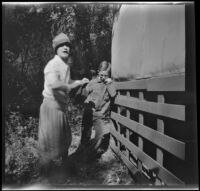 Mertie West and H. H. West, Jr. stand by the side of a structure, Ojai vicinity, about 1925
