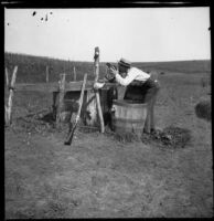 H. H. West drinks from a bucket filled with water from a spring, Elliott vicinity, 1900