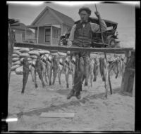 Glen Velzy posing with fish and a fishing rod, Newport Beach, 1914