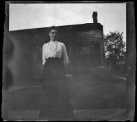 Woman stands in front of a house, Ottumwa, 1900