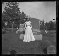 Ellen Lorene (Pinkie) Lemberger poses in front of a headstone, Ottumwa, 1900