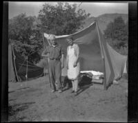 Forrest and Agnes Whitaker stand in front of a tent at a camp, Inyo County vicinity, about 1930