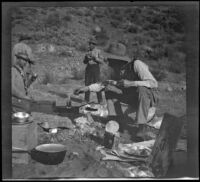 Elmer Cole cooking fish while Al Schmitz, Otto Schmitz and Charles Stavnow eat, Los Padres National Forest, about 1915