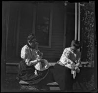 Grace Butterfield and Claude Bishop sit on a porch holding children on their laps, Red Oak, 1900