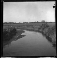 Nishnabotna River with trees in the background and brush on either shore, Red Oak, 1900