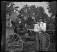 Carl Austin sits on a buggy while Frank Iddings stands next to it, Red Oak, 1900