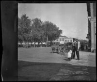 Two men and a girl stand in the town square, Red Oak, 1900