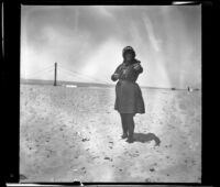 Mary Whitaker standing on the beach and pointing to the camera, Redondo Beach, 1901
