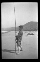 H. H. West, Jr. stands on the beach at Rincon Point and looks towards the ocean, Carpinteria vicinity, about 1924
