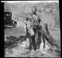 H. H. West Jr. holds fish and fishing gear, Mono County vicinity, 1929