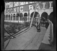 People stand behind a fence watching a miniature railroad, San Francisco, 1900