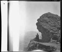 Visitors to Mount Tamalpais stand beneath a rock formation and gaze over the mountainside, Marin County, about 1900