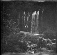 H. H. West stands on a rock below Burney Falls, Burney, 1915