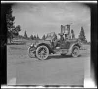 Harry Schmitz and Wilfrid Cline, Jr. sitting in H. H. West's Buick while parked in front of a water tank, Truckee vicinity, 1917