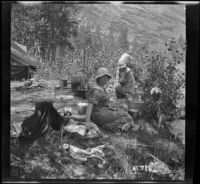 Mary A. West sitting in camp with Chester and Kate A. Schmitz in the background, June Lake vicinity, 1914