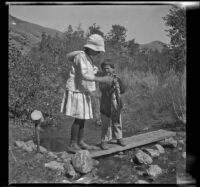Elizabeth West helps Chester Schmitz pose for a photograph with fish, June Lake vicinity, 1914