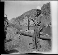 Howard Buttress posing with a fish while France West watches, June Lake vicinity, 1914