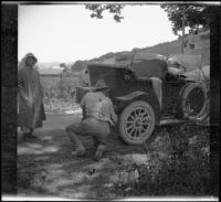 Dave F. Smith fixing a tire on his EMF while Mary A. West watches, San Juan (vicinity), 1913
