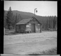 Log cabin standing along the roadside in Phillips, Eldorado National Forest, 1913