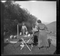 Dave F. Smith carries water into camp while Isabelle Smith and Nella West prep food, Carson City (vicinity), 1913