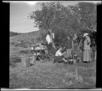 Dave F. Smith, Isabelle Smith, Nella West and Mary A. West eating and prepping food in camp, Mono County, 1913
