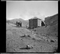 Mary A. West, Nella A. West, Dave F. Smith and Isabelle West stand in a group by a shack at a hot spring, Mammoth Lakes vicinity, 1913