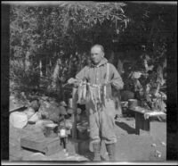 H. H. West posing in camp with the limit of golden trout, Inyo County, 1913