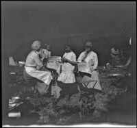 Mary A. West, Frances West, Irene Schmitz and Kate Schmitz gathered near a table in their camp at Oak Grove, Warner Springs vicinity, about 1915