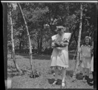 Girl holding a pet monkey in the Oak Grove camp while Irene Schmitz watches, Warner Springs vicinity, about 1915