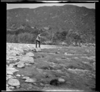 H. H. West fishing while standing atop a rock in the San Gabriel River, San Gabriel Canyon, about 1903