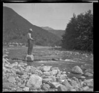 Will P. Mead stands atop a rock and fishes in the San Gabriel River, San Gabriel Canyon, about 1903