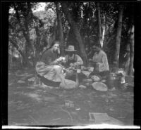 Mary A. West, Will P. Mead and Sena Mead dine at their camp table, San Gabriel Canyon, about 1903