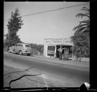 Man leans on a sign in front of Stewart's Home Grown Fruit stand, Santa Ana, 1937