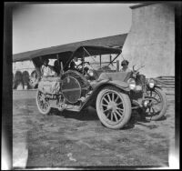 H. H. West's Buick parked in front of Santa Barbara Mission with Wilhelmina, Frances, and Elizabeth West inside and Mary West beside it, Santa Barbara, 1915