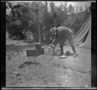 Al Schmitz organizing the cooking supplies while standing next to the camp stove, Santa Ynez River vicinity, 1919