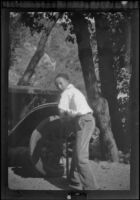 H. H. West, Jr. pumping air into a car's tire at Sunset Canyon Country Club, Burbank, about 1927