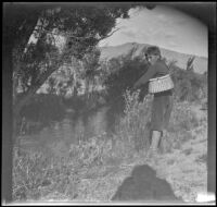 Wilfrid Cline, Jr. poses while fishing Taboose Creek, Big Pine vicinity, about 1918