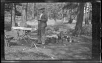 Frank Beckett stands by the camp table, Yosemite National Park, about 1923